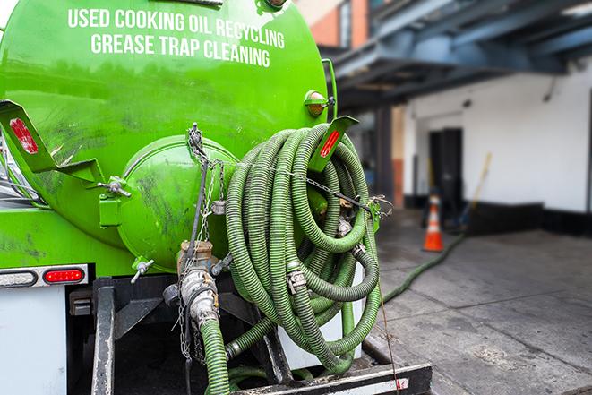 a technician pumping a grease trap in a commercial building in Haslett